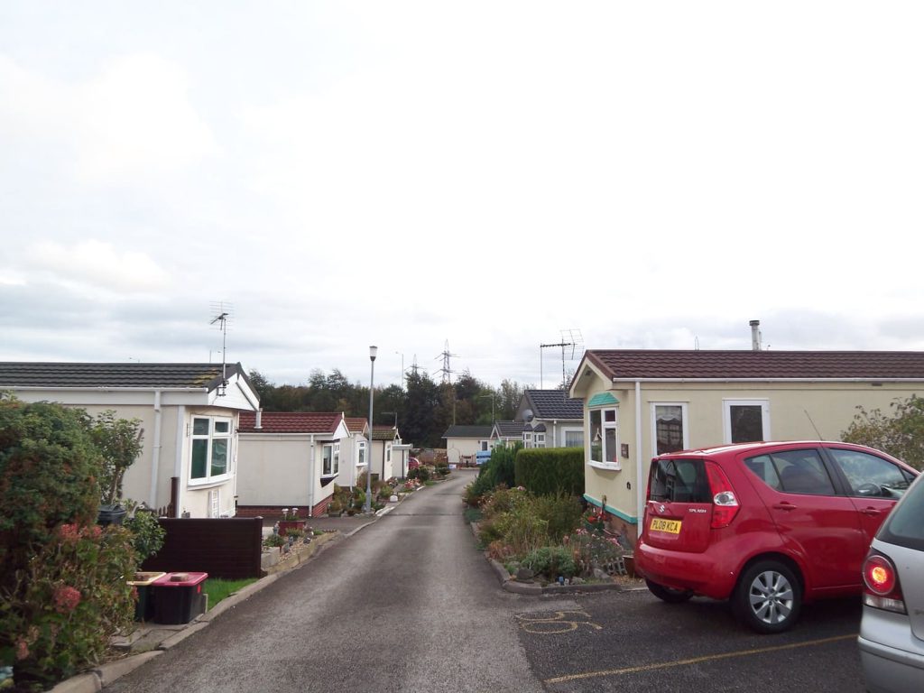 http://A%20road%20filled%20with%20lodges%20on%20either%20side.%20There%20are%20cars%20parked%20on%20either%20side%20of%20the%20road.